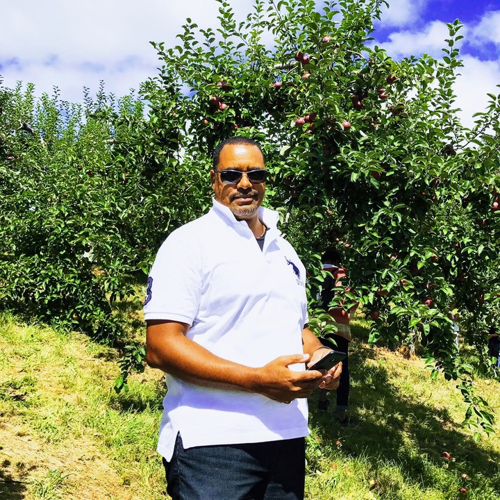 Calvin Tilokee apple picking with a phone in his hand