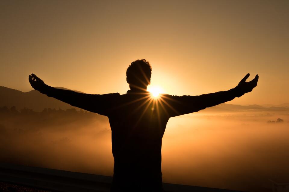 Man with outstretched arms overlooking sunset